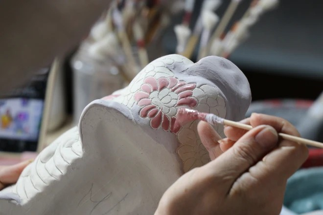 Artistas aplican esmalte y dibujan patrones en productos cerámicos de Bien Hoa en el horno de alfarería de Phong Son. (Fuente:VNA)