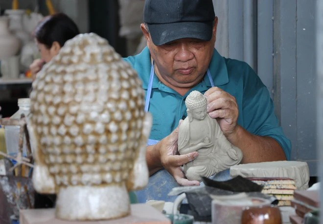 El artista Le Thanh Nhan ha estado involucrado con la cerámica de Bien Hoa durante más de 30 años, elaborando una estatua de Buda de cerámica. (Fuente:VNA)