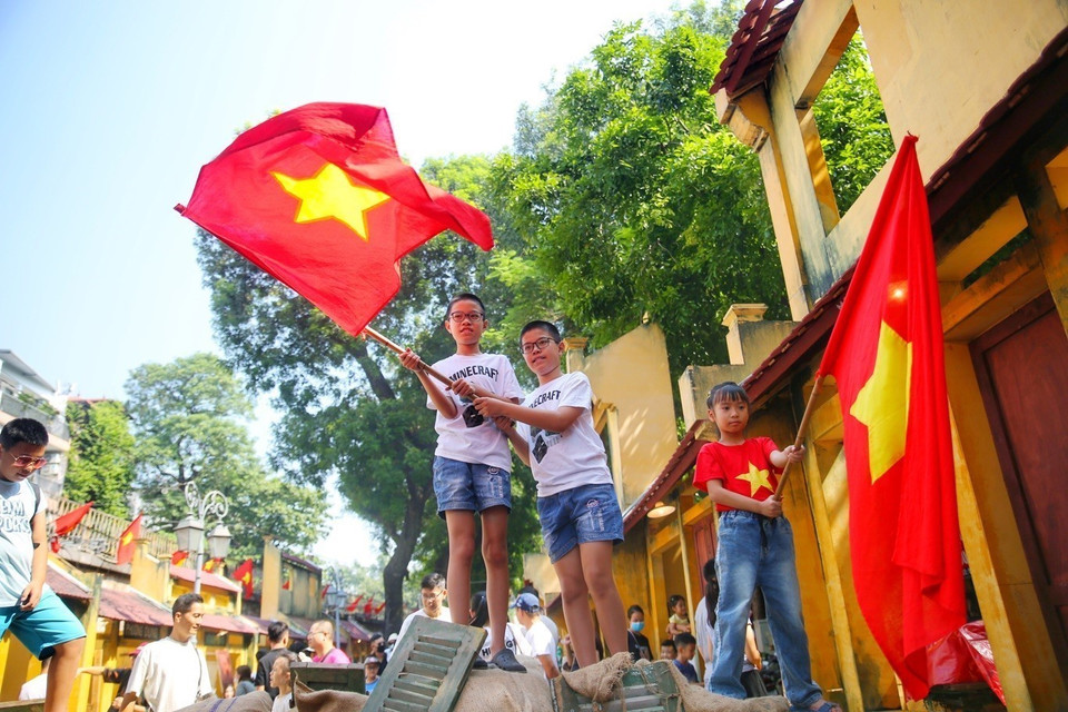 Niños con la Bandera Nacional en la calle mural de Phung Hung. (Fuente:VNA)