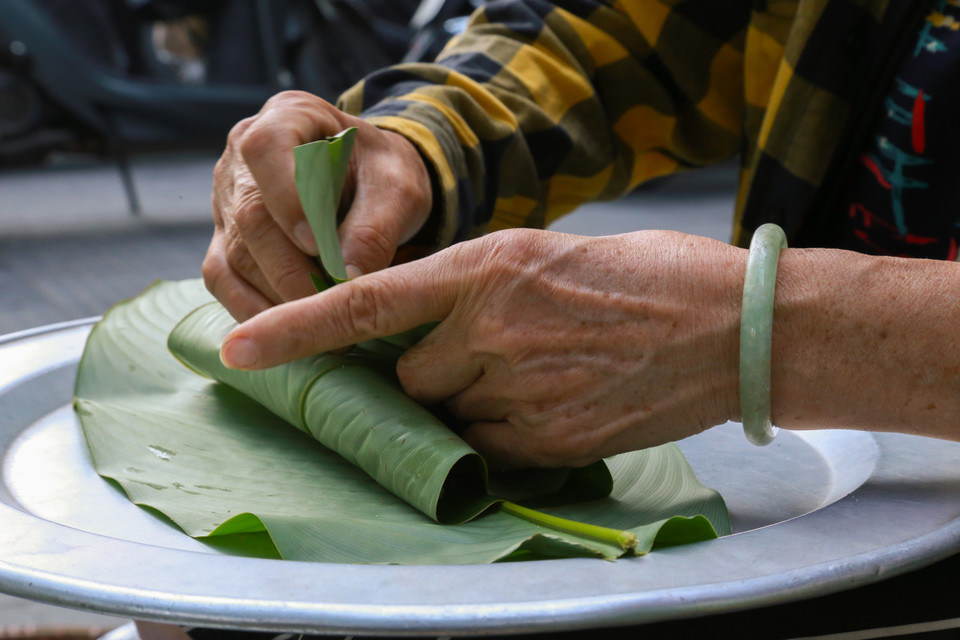 Los granos de arroz verde se envuelven meticulosamente en hojas de loto y se atan con tiras antes de ser entregados al comprador. Foto: Quynh Anh/VNA