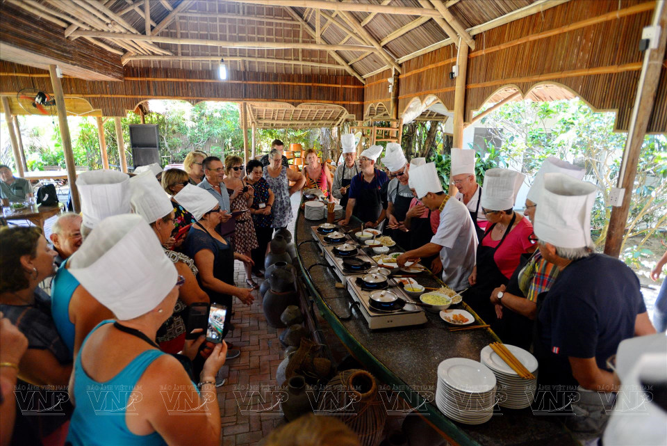 Los turistas foráneos participan en una clase de cocina de un restaurante en la aldea de Tra Que (Foto: VNA)