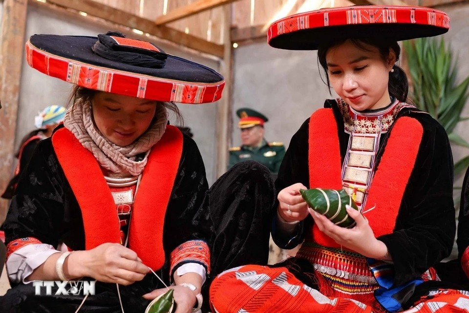 Una turista de Hanoi, vestida con ropa tradicional de los Dao rojo, participa emocionada en la elaboración del banh chung gu (la versión noroeste del banh chung). (Foto: VNA)