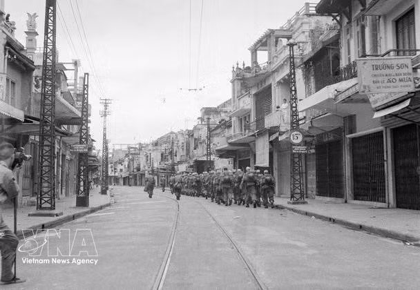 Conforme a los Acuerdos de Ginebra, las fuerzas francesas disponían de 80 días para retirarse de Hanoi. El 8 de octubre arriaron su bandera y el 9 de octubre comenzaron la retirada de la capital. A medida que se retiraban, las tropas vietnamitas asumían el control. A las 16:30 horas del 9 de octubre, las últimas tropas francesas cruzaron el puente Long Bien rumbo a Hai Phong, quedando Hanoi completamente bajo control vietnamita. En la imagen, soldados franceses se retiran por la calle Hang Dao hacia el puente Long Bien. (Foto: Archivo de VNA)