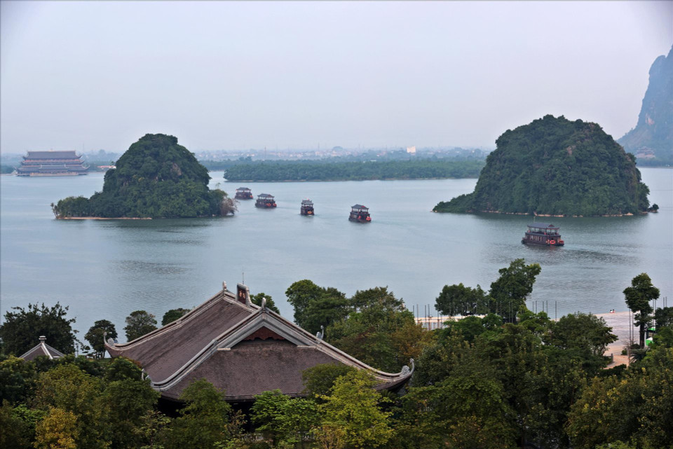 2. Los barcos pequeños se deslizan suavemente sobre el agua, creando un entorno poético al acercarse al complejo de la pagoda. (Foto: VNA)