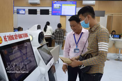 En la ciudad de Dong Nai, funcionarios del Centro de Servicios Administrativos Públicos orientan a los ciudadanos sobre cómo buscar información acerca de los trámites administrativos a través del sistema de IA. Foto: VNA.