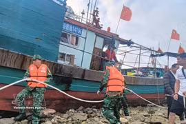 Oficiales y soldados de la Guardia Fronteriza de Hai Phong ayudan a un pesquero chino a asegurar sus amarras mientras esperan condiciones climáticas favorables para ser remolcado al puerto. (Foto: VNA)