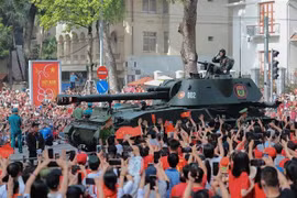 Los pobladores saludan a las formaciones de tanques y vehículos blindados. (Foto: VNA)