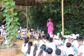 Los niños escuchan con atención a la guía turística mientras les cuenta sobre la infancia del Presidente Ho Chi Minh. (Foto: VNA)
