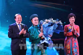 La directora general de la VNA, Vu Viet Trang (derecha), y el viceministro de Cultura, Deportes y Turismo, Ta Quang Dong (izquierda), entregan el premio de Artista inspirador a Chu Bao Que. (Foto: VNA)