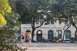 Turistas extranjeros pasean bajo los árboles frondosos a orillas del lago Hoan Kiem, disfrutando del ambiente fresco de la capital. (Foto: VNA)
