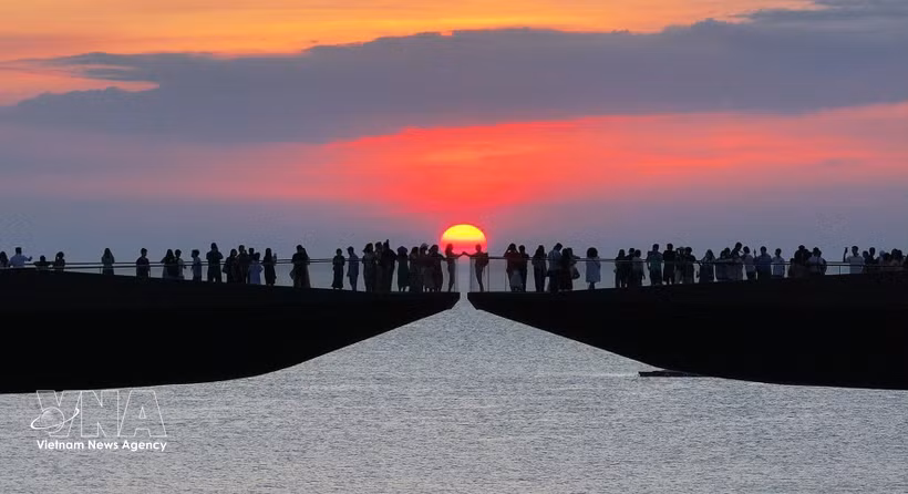 Turistas contemplan la puesta de sol en el Puente del Beso, en la zona especial de Phu Quoc (provincia de An Giang). (Foto: VNA)
