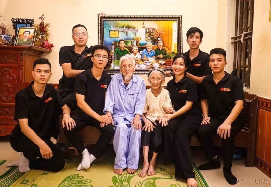 Phung Quang Trung (fila superior, a la derecha) y el equipo de restauración de fotografías de Skyline han restaurado miles de fotografías de mártires para rendir homenaje a aquellos que se sacrificaron por la independencia y la libertad de la Patria, contribuyendo al acto social de "Devolver la gratitud". En la foto: Presentando a la heroica madre vietnamita Nguyen Thi Ngach una foto que simula una comida de reencuentro con sus dos hijos. (Foto: VNA)