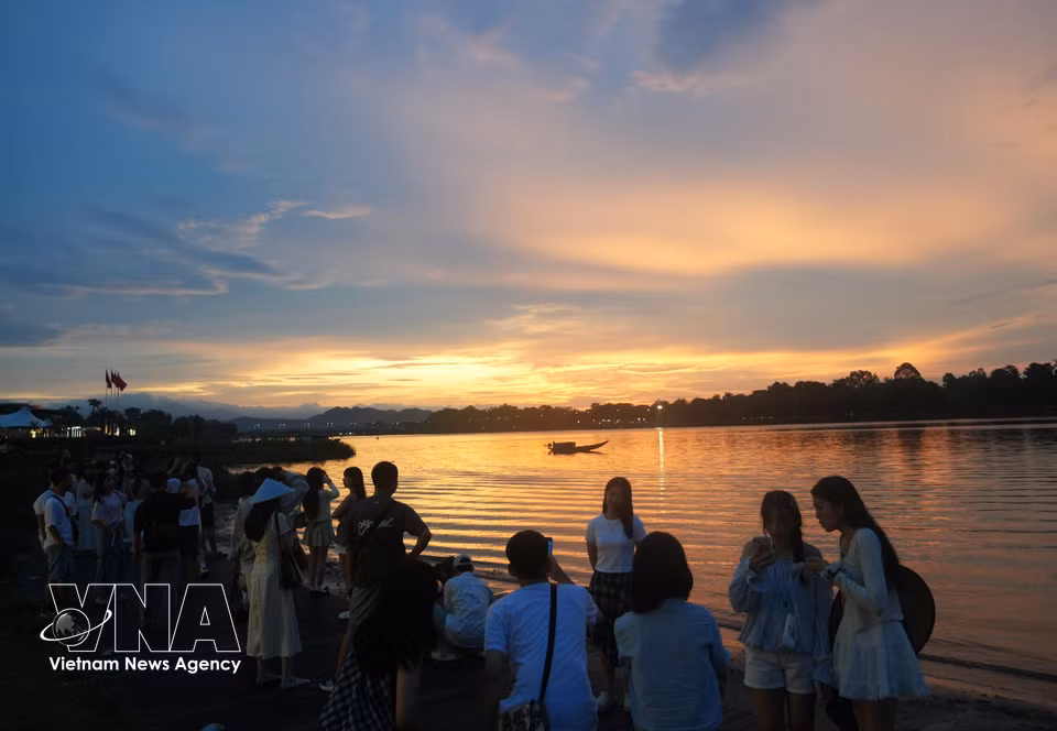 Turistas disfrutan de la puesta de sol en la orilla del río Perfume en la ciudad de Hue durante el Día Nacional, 2 de septiembre. Foto: VNA