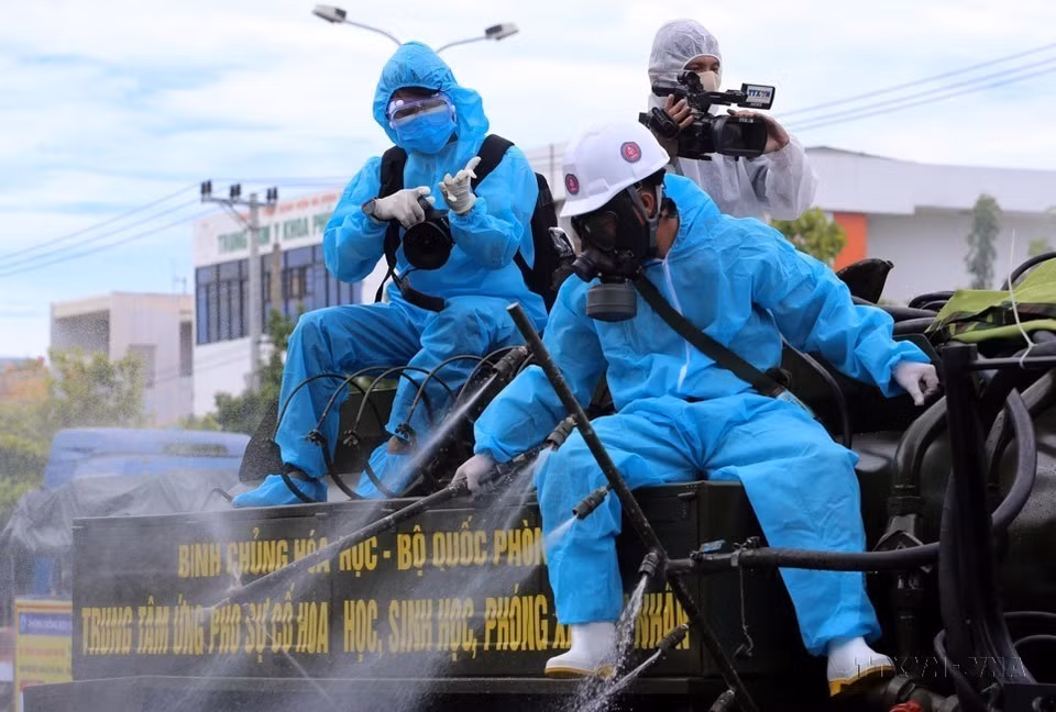 Un reportero de la Agencia Vietnamita de Noticias trabaja en la parte trasera de un vehículo para rociar desinfectante en áreas con alto riesgo de infección por COVID-19 en el distrito de Son Tra, en la ciudad de Da Nang. (Fuente: VNA)